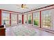 Bright sunroom with multiple windows, a ceiling fan, colorful area rug, and a decorative shelf lined with miniature houses at 210 Lawn Market, Sharpsburg, GA 30277