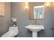 Elegant powder room featuring a pedestal sink, decorative mirror, and stylish lighting fixtures at 3172 Ashford Dunwoody Ne Rd, Brookhaven, GA 30319