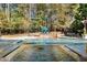 Backyard swimming pool and patio area surrounded by trees at 1050 Carnoustie Ln, Alpharetta, GA 30005