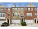Townhouse exteriors showcase brick facades, white garage doors, and manicured landscaping under a bright sky at 4662 Creekside Villas Se Way, Smyrna, GA 30082