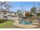 The backyard has a luxurious pool with a waterfall feature surrounded by lush landscaping and grass at 1524 Chateau Dr, Dunwoody, GA 30338