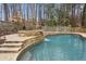 The backyard has a swimming pool with a stone waterfall feature surrounded by a wooden fence at 1524 Chateau Dr, Dunwoody, GA 30338