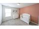 Bright Bedroom with a white crib, dresser, and pink accent wall at 1935 Azure Grove Ct, Marietta, GA 30008