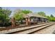 Refurbished historic train station with a brick fence line, mature trees, and train tracks at 204 College Cir # 1003, Hapeville, GA 30354