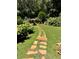 Beautiful backyard landscape featuring a stone pathway and outdoor kitchen in a wooded setting at 1050 Silver Thorne Dr, Loganville, GA 30052