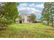 Large backyard with lush green grass surrounding a charming two-story home with tan siding and a cozy patio at 3641 Willow Club Dr, Loganville, GA 30052
