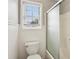 Bright bathroom featuring white wainscoting, a toilet, and a shower with sliding doors and a window at 3641 Willow Club Dr, Loganville, GA 30052