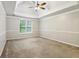 Large carpeted bedroom featuring tray ceilings, ceiling fan and trim at 3641 Willow Club Dr, Loganville, GA 30052