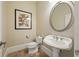 Powder room with pedestal sink, oval mirror, neutral walls, and decorative art at 9070 Waits Ferry Xing, Johns Creek, GA 30097