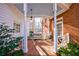 Inviting brick front porch with a cozy swing, complemented by white columns and manicured greenery at 2650 Peachtree Battle Nw Pl, Atlanta, GA 30327