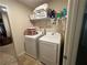 Bright laundry room featuring a washer and dryer with a wire shelf and tiled floors at 1720 Danville Dr, Mcdonough, GA 30253