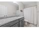 Well-lit bathroom with gray vanity, granite countertop, white shower curtain, and wood-like tile floors at 2066 Charcoal Ives Rd, Lawrenceville, GA 30045