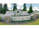 Landscaped entrance sign for Water Oak Estates, surrounded by lush greenery and seasonal flowers at 1818 Lacebark Elm Way, Lawrenceville, GA 30045