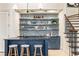 Stylish basement bar features a dark countertop, blue cabinets, floating shelves, and a mini fridge at 675 W Paces Ferry Nw Rd, Atlanta, GA 30327