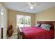 Bright bedroom featuring a bed with a red comforter, ceiling fan, and a window with natural lighting at 6884 Robinson St, Lithonia, GA 30058