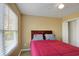 Bedroom featuring a queen-size bed with red comforter, a ceiling fan, and natural light from window at 6860 Robinson St, Lithonia, GA 30058