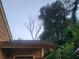 Home exterior with dark roof, matching gutters, and mature trees in an overgrown lawn at 1767 Thomas St, Decatur, GA 30032