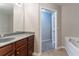 Bathroom features wood cabinet, grey countertop, tub, and doorway to another room at 2890 Ridgeview Sw Dr, Atlanta, GA 30331