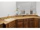 Elegant wet bar with wood cabinets, granite countertops, and brass faucet offering a touch of luxury at 6995 Polo Fields Pkwy, Cumming, GA 30040