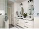 A bright, stylish bathroom features dual sinks with black fixtures, white cabinetry, and a glass-enclosed shower at 1602 Windsor Walk, Avondale Estates, GA 30002