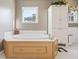 Bright bathroom features a soaking tub with wood trim and a white linen cabinet at 1650 Old Loganville Rd, Loganville, GA 30052