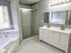 Bright bathroom with a double vanity, glass shower, a soaking tub under a window, and a black and white patterned tile floor at 1666 Hearthstone Way, Jonesboro, GA 30236