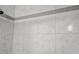 Close up of a shower with white marble-look tile and a gray accent tile border at 1666 Hearthstone Way, Jonesboro, GA 30236