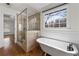 Bright bathroom with a freestanding tub, glass shower, and large window overlooking the wooded backyard at 2321 Birdie Ln, Duluth, GA 30096