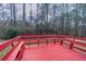 Red wooden deck featuring built-in bench seating, perfect for enjoying the surrounding nature and relaxing outdoors at 3174 Palm Tree Dr, Lithonia, GA 30038