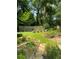 Serene backyard with garden beds, including barrel planters, manicured lawn, stone pathway, and mature trees, offering a peaceful retreat at 437 Westmeath Sw Dr, Atlanta, GA 30310