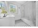 Well-lit bathroom featuring a sink, shower with a white curtain, and patterned floors at 437 Westmeath Sw Dr, Atlanta, GA 30310