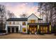 Stunning modern farmhouse exterior featuring a mix of brick and white siding, perfectly manicured lawn, and statement lighting at 185 Pebble Trl, Alpharetta, GA 30009