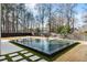 Backyard oasis with a modern pool, lounge chairs, and a serene garden with mature trees at 185 Pebble Trl, Alpharetta, GA 30009