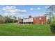 View of the brick home and spacious backyard lawn under a partly cloudy sky at 3113 Melissa Ct, Douglasville, GA 30135