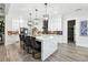 A modern kitchen features an island with seating and pendant lights, as well as white cabinets at 557 Loth Wages Rd, Dacula, GA 30019