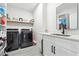 Well-lit laundry room featuring modern washer and dryer, sink with white cabinets, and a convenient storage shelf at 557 Loth Wages Rd, Dacula, GA 30019