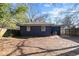 Exterior shot of the backyard with a dark blue home, small windows, and a wood fence at 1889 Cannon St, Decatur, GA 30032