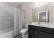 Bathroom featuring a shower with marble-look tiles, a dark vanity, and a mirror above the sink at 380 Parkside Meadow Sw Dr, Marietta, GA 30064