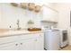 Bright laundry room featuring a sink, counter space, and modern white appliances and cabinets, ideal for efficient chore management at 765 Glengate Pl, Atlanta, GA 30328
