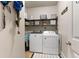 Practical laundry room with washer, dryer, shelving for storage and neutral walls at 5211 Centennial Hill Nw Dr, Acworth, GA 30102