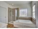 Bright bathroom with large tub, decorative window, and glass shower enclosure at 3769 Baxley Point Dr, Suwanee, GA 30024