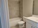 Tiled bathroom features a shower over the tub and a white vanity with grey floor tiles at 452 Eagles Nest Cir, Auburn, GA 30011
