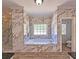 Luxurious bathroom with marble tiling, soaking tub, and a glass-enclosed shower at 5780 Warren Farm Sw Rd, Powder Springs, GA 30127