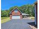 Exterior of the garage and carport with well maintained asphalt driveway and landscaping at 5780 Warren Farm Sw Rd, Powder Springs, GA 30127