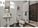 Modern bathroom with pedestal sink, toilet, shower with black tile, and modern sconces at 805 Peachtree Ne St # 317, Atlanta, GA 30308