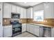 Well-lit kitchen featuring stainless steel appliances, granite countertops, and white cabinetry at 907 Southfork Dr, Loganville, GA 30052