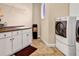 Well-lit laundry room with washer, dryer, white cabinets, sink, and a unique circular window at 1069 Eagles Brooke Dr, Locust Grove, GA 30248