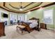 Spacious main bedroom featuring a tray ceiling, carpet, a sitting area, and large windows at 1069 Eagles Brooke Dr, Locust Grove, GA 30248