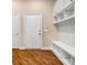 Inviting mud room with wood floors, white storage cabinets, shelving, coat hooks, and bench seating at 1069 Eagles Brooke Dr, Locust Grove, GA 30248