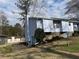 View of the light blue home with stone foundation, showcasing the side yard and surrounding landscape at 1454 Walnut Log Pl, Austell, GA 30168